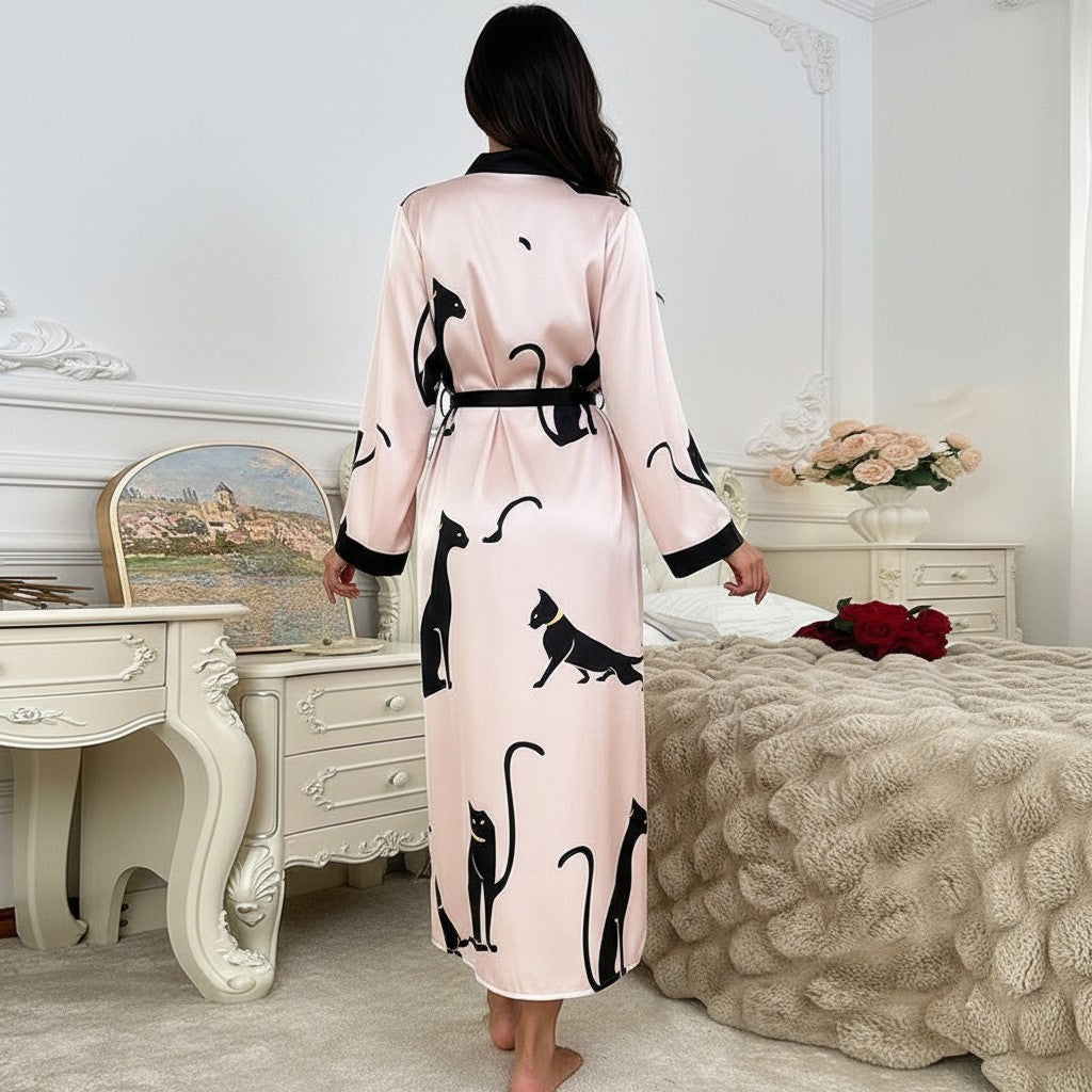 Bata larga de satén rosa con estampado de gatos negros de vestismuse, vista trasera en dormitorio elegante.