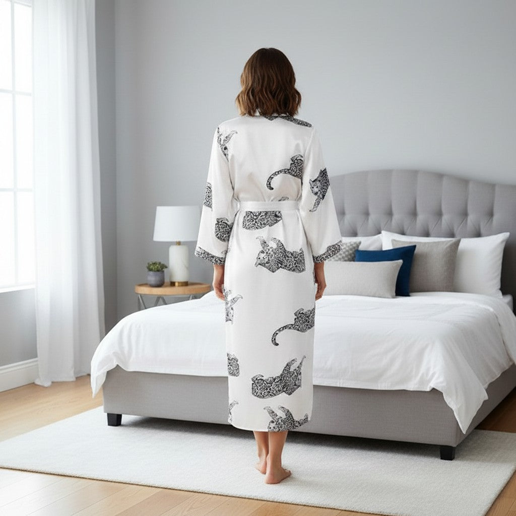 Mujer de espaldas vistiendo bata larga de satén Vestismuse con estampado de leopardo en dormitorio moderno.