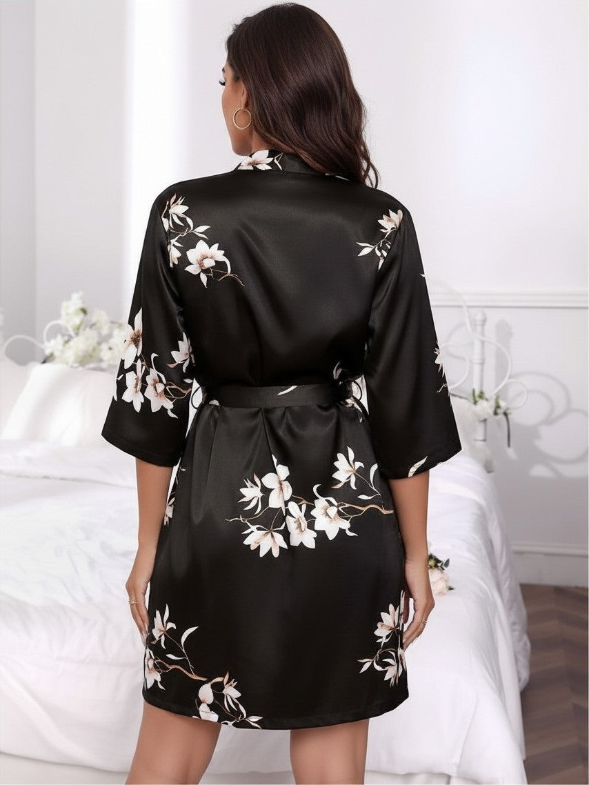 Bata corta de satén negro con estampado floral de vestismuse, vista trasera sobre modelo en dormitorio elegante.