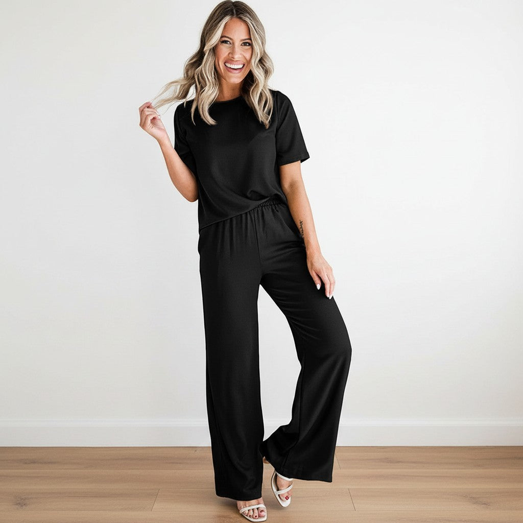 Mujer sonriente vistiendo el conjunto satinado negro de dos piezas de vestismuse con pantalón fluido y camiseta