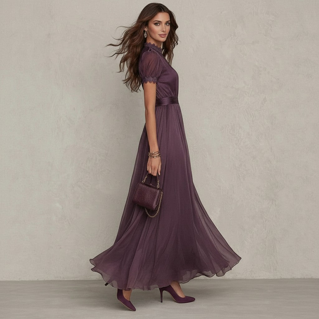 Modelo luciendo el vestido largo Amélie de vestismuse en color morado, con encaje, cuello alto y mangas abullonadas.