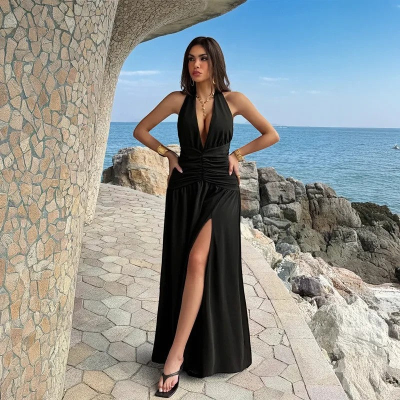 Modelo con vestido largo negro VestisMuse de escote halter, espalda descubierta y abertura lateral junto al mar